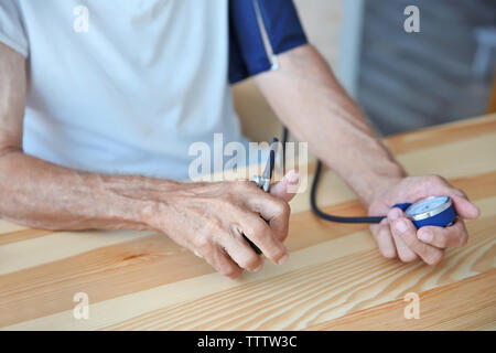 Senior man measuring pressure on wooden table Stock Photo