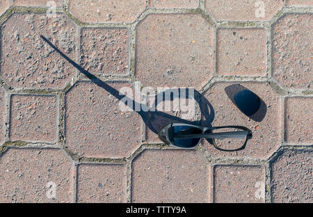 the broken sunglasses lying on the flagstone pedestrian walkway Stock Photo
