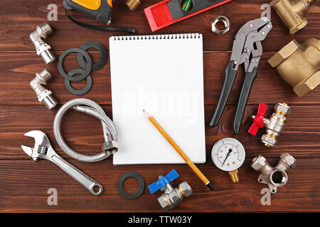 Notebook and plumber tools on wooden background Stock Photo
