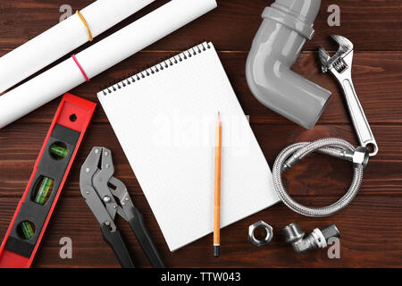 Notebook and plumber tools on wooden background Stock Photo