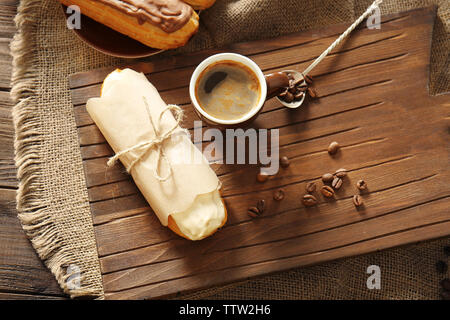 Tasty eclair and cup of coffee on wooden background Stock Photo