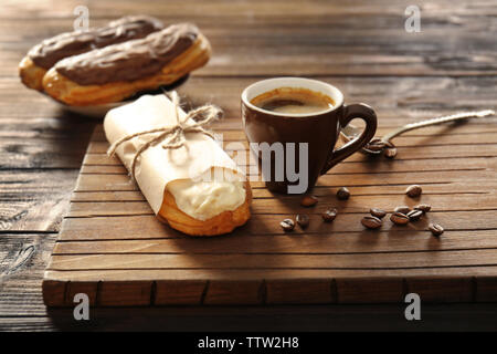 Tasty eclair and cup of coffee on wooden background Stock Photo