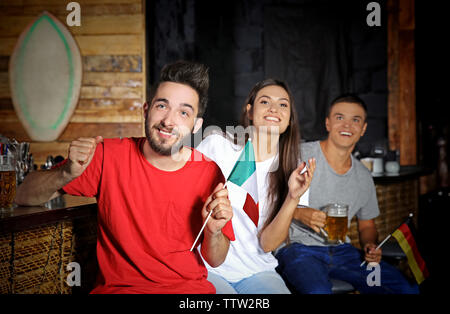 Cheerful friends emotionally watching soccer game in sport bar Stock Photo