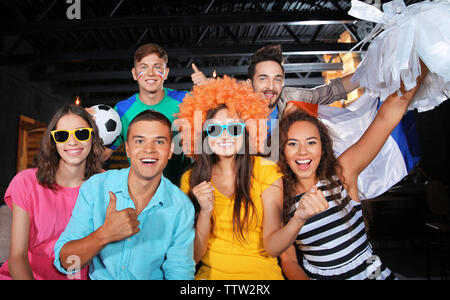 Cheerful friends with France flag emotionally watching soccer game in sport bar Stock Photo