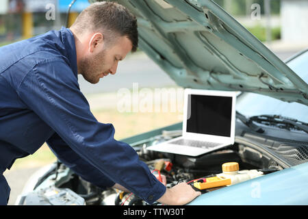 Mechanic using computer diagnostics while repairing car Stock Photo