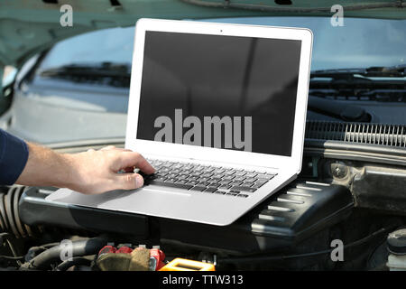 Mechanic using computer diagnostics while repairing car Stock Photo