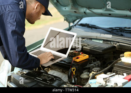 Mechanic using computer diagnostics while repairing car Stock Photo