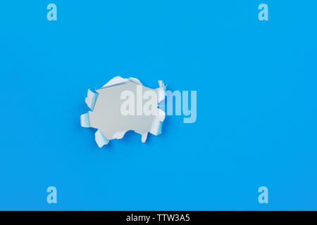 Vivid blue paper with ripped torn hole and copy space for text. Texture / design element image. Stock Photo