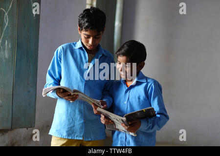 Two schoolboys reading books in a classroom Stock Photo