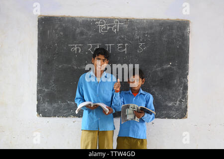 Two schoolboys reading books in a classroom Stock Photo