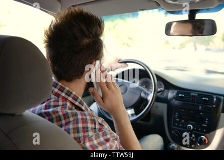 Young handsome driver using mobile phone while driving car Stock Photo
