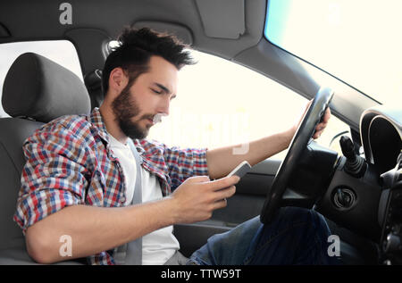 Young handsome driver using mobile phone while driving car Stock Photo
