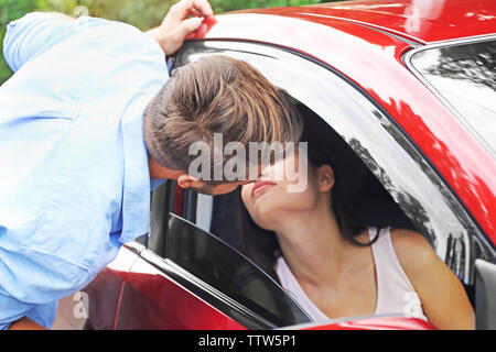 Handsome man almost kissing pretty young woman sitting in car Stock Photo