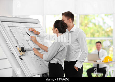 Two young creative engineers working with project on drawing board Stock Photo