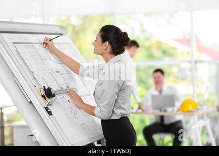 Young creative female engineer working with new project on drawing board Stock Photo
