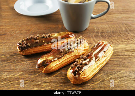 Delicious eclairs and cup on wooden table Stock Photo