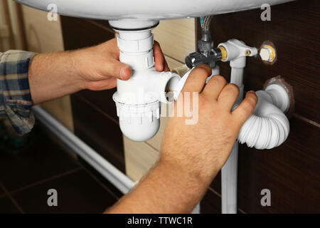 Hands of plumber assembling sink pipes, close up view Stock Photo