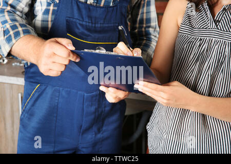 Woman writing on worker clipboard, close up view Stock Photo