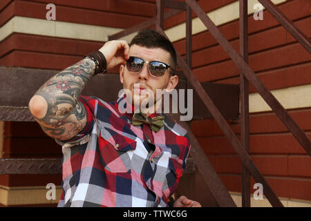 Young tattooed man posing on stairs, outdoor Stock Photo
