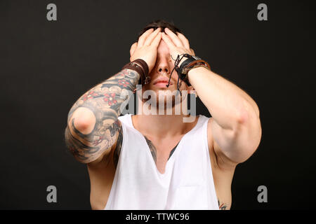 Young tattooed man posing on dark background Stock Photo