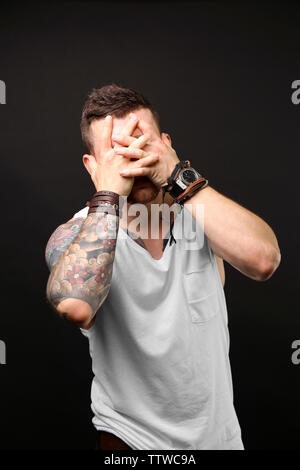 Young tattooed man posing on dark background Stock Photo