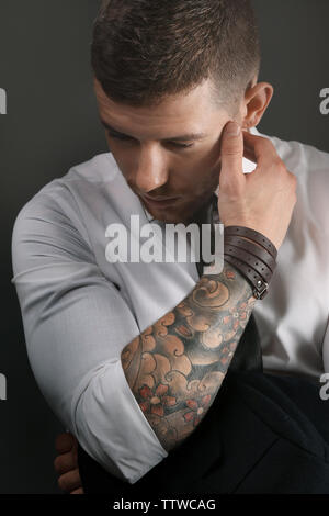Young tattooed man posing on dark background Stock Photo