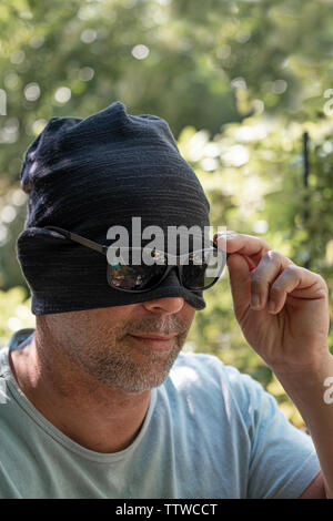 mature bearded man hiding his face under a knitted hat Stock Photo