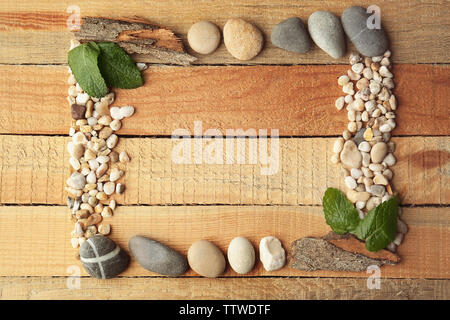 Rectangular frame made of pebbles, leaves and bark on wooden background Stock Photo