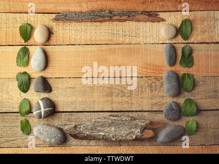 Rectangular frame made of pebbles, leaves and bark on wooden background Stock Photo