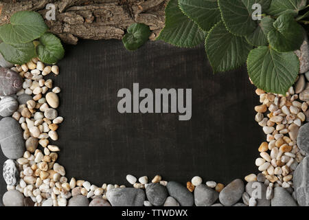Rectangular frame made of leaves, pebbles and bark on dark background Stock Photo