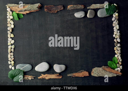 Rectangular frame made of leaves, pebbles and bark on dark background Stock Photo