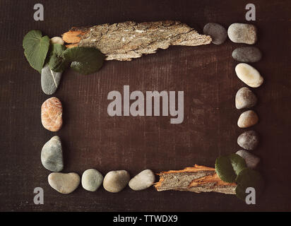 Rectangular frame made of leaves, pebbles and bark on brown background Stock Photo