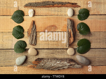 Rectangular frame made of pebbles, leaves and bark on wooden background Stock Photo