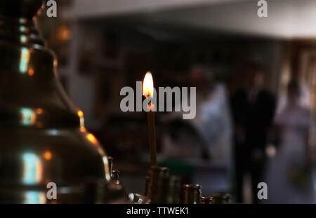 Burning candle on blurred wedding ceremony in church Stock Photo