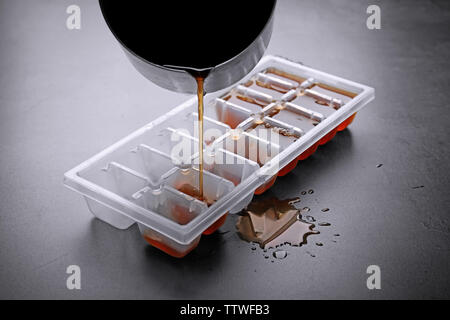 https://l450v.alamy.com/450v/ttwfb3/pouring-coffee-in-ice-cube-tray-on-grey-background-ttwfb3.jpg