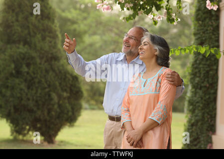 Old couple standing in a lawn Stock Photo