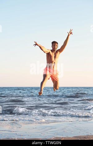 Happy man jumping on beach Stock Photo