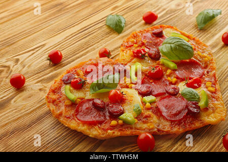 Tasty heart shaped pizza on wooden background Stock Photo