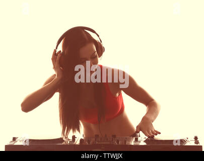 Portrait of pretty young DJ playing music on light background Stock Photo