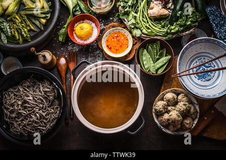 Various asian food ingredients for tasty soba noodles soup around cooking pot with delicious miso broth or stock on rustic kitchen table background, t Stock Photo