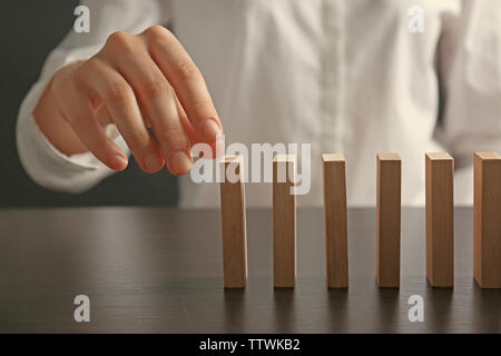 Businesswoman hand trying to toppling dominoes on table Stock Photo