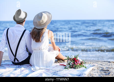 Young happy couple sitting back on beach Stock Photo