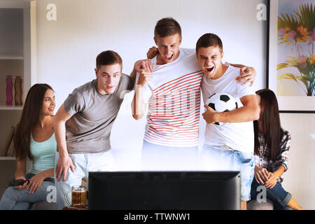 Young fans watching football match on TV Stock Photo