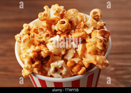 Caramel popcorn in striped box on wooden background Stock Photo