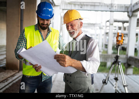 Engineer and construction site manager dealing with blueprints and plans Stock Photo