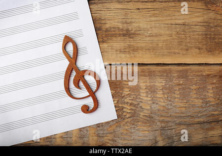 Treble clef and sheet of paper on wooden background Stock Photo