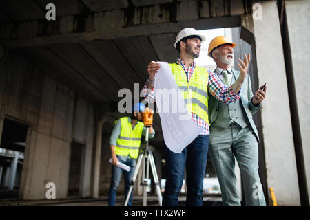 Engineer, foreman and worker discussing in building construction site Stock Photo