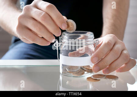 Man hand putting money in glass jar Stock Photo