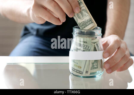 Man hand putting money in glass jar Stock Photo