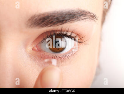 Young woman putting contact lens in her eye, close up view. Medicine and vision concept Stock Photo